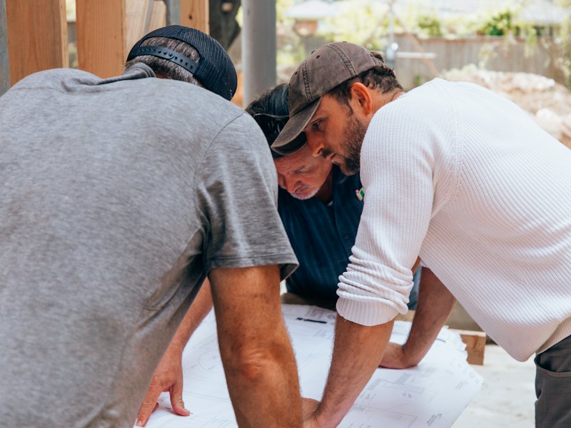 Construction crew reviewing plans together on a home remodeling job site